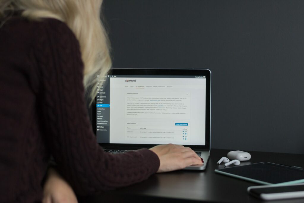 Girl using Macbook Pro to reset her WordPress site with a free plugin